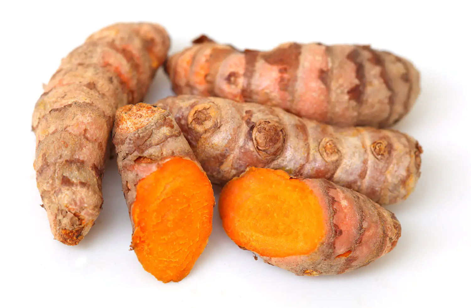 Curcuma longa Wurzeln Frische Kurkumawurzeln auf weißem Hintergrund, einige halbiert, orangefarbenes Fruchtfleisch sichtbar, insgesamt fünf Stück.