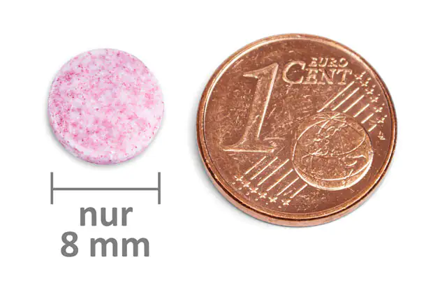 Brausetablette 8 mm – rosa Rosa Brausetablette mit einem Durchmesser von 8 mm neben einer 1-Cent-Münze für Größenvergleich.