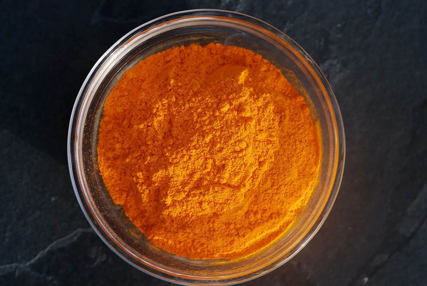 Curcuma longa Pulver Oranges Kurkuma Pulver in einem Glasbehälter, 100 g, von oben aufgenommen.